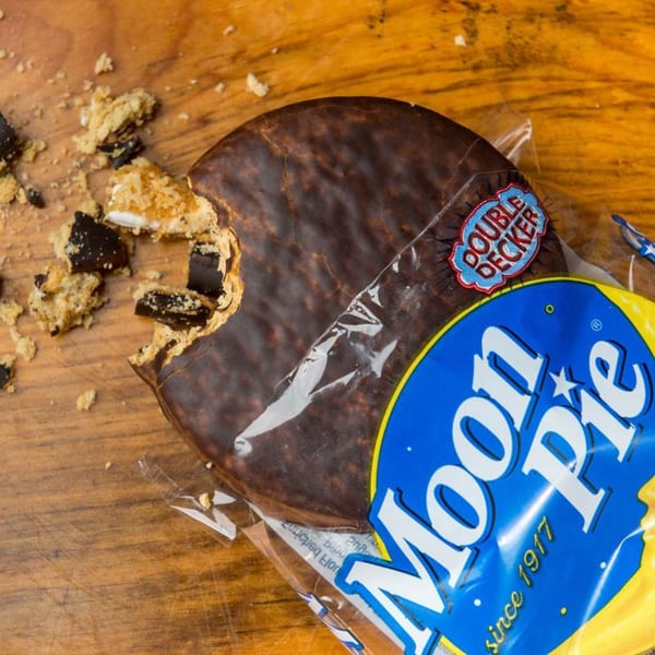A partially eaten Moon Pie in its wrapper, with crumbs scattered on a wooden surface.