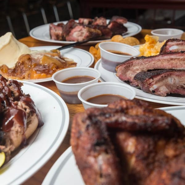 A table laden with Yazoo BBQ dishes, including ribs, pulled pork, apple pie, and sauces.